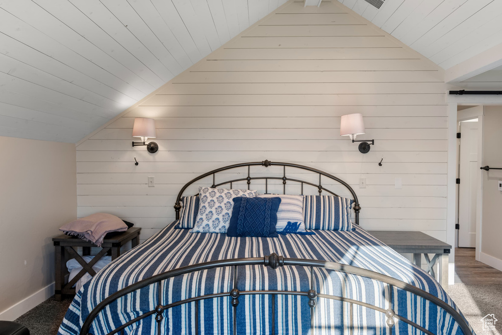Bedroom with vaulted ceiling, wood walls, wood ceiling, and baseboards