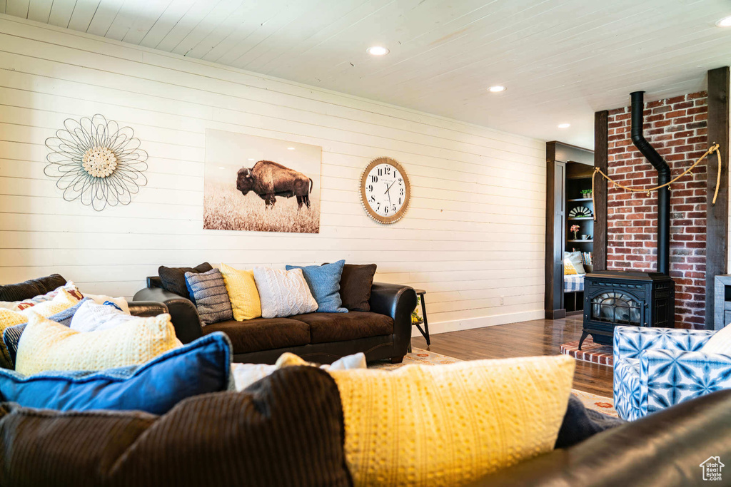 Living area with wood finished floors, a wood stove, wood walls, wooden ceiling, and baseboards