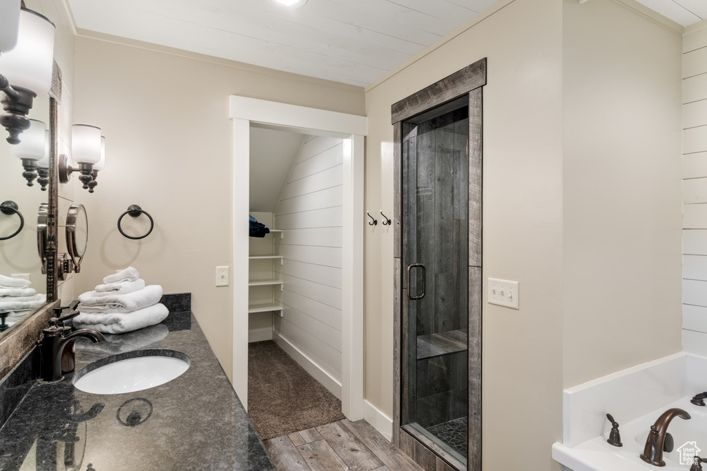 Full bathroom with a stall shower, a garden tub, vanity, wood finished floors, and a spacious closet