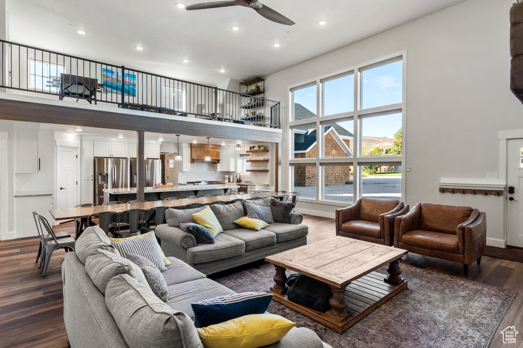 Living area featuring a high ceiling, ceiling fan, dark wood-style flooring, and recessed lighting