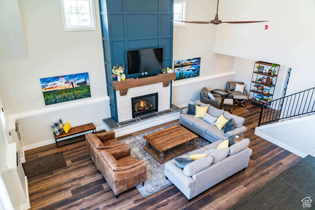 Living area featuring wood finished floors, a fireplace, a high ceiling, baseboards, and ceiling fan