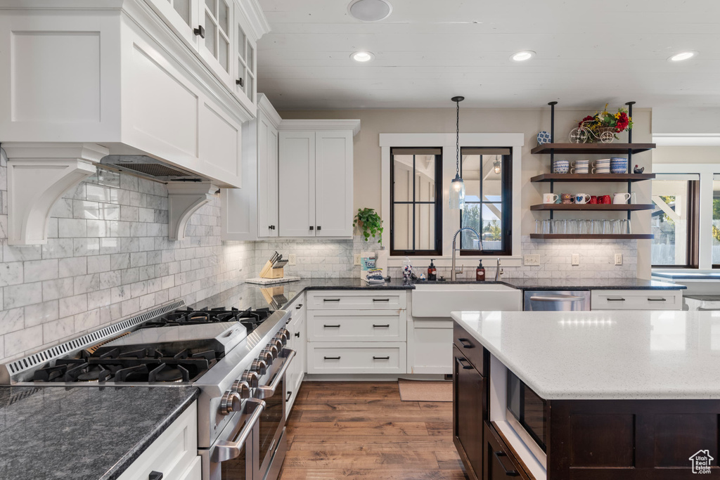 Kitchen with stainless steel appliances, a sink, open shelves, tasteful backsplash, and white cabinetry