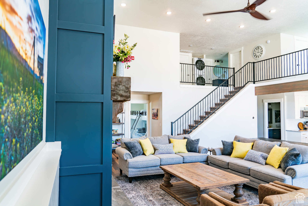 Living area featuring stairway, recessed lighting, a ceiling fan, and a high ceiling