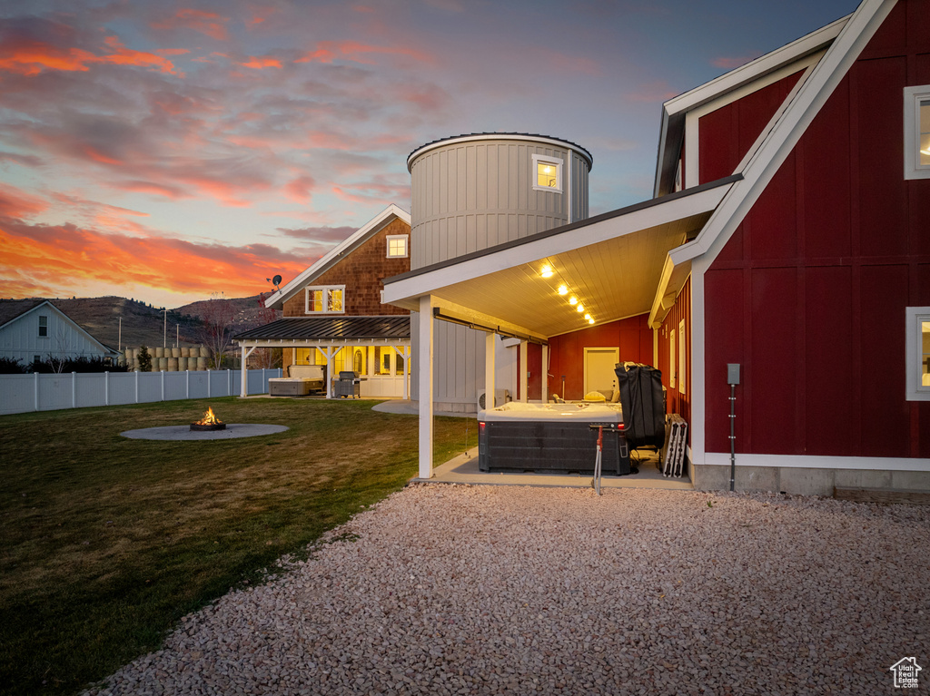 Back of property with a fire pit, a hot tub, and a patio area