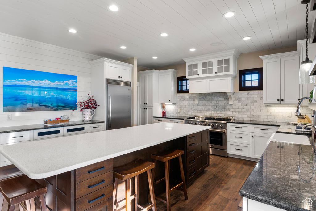 Kitchen with high end appliances, a sink, a breakfast bar, a center island, and recessed lighting