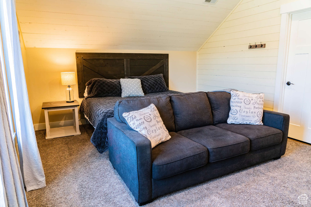 Carpeted bedroom with lofted ceiling and wood walls