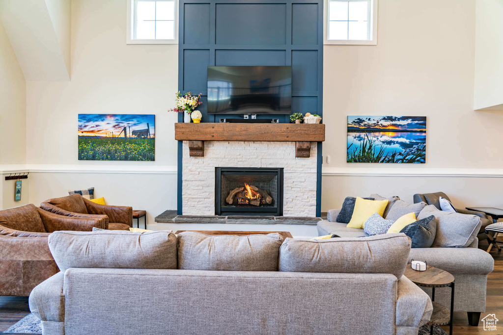 Living area featuring healthy amount of natural light, a stone fireplace, and wood finished floors