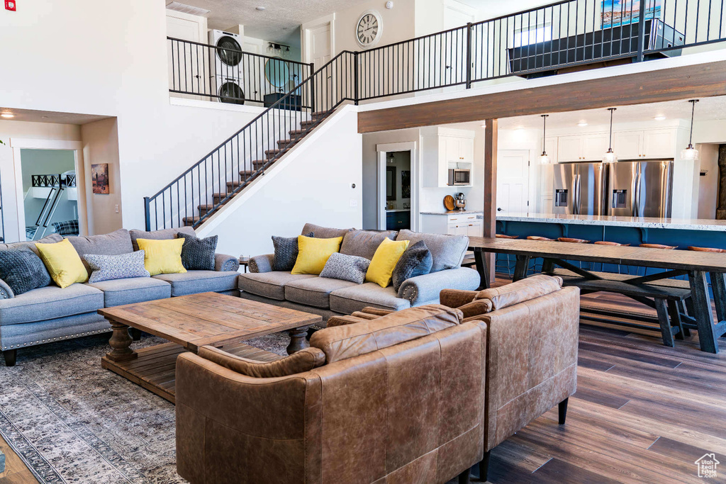 Living area featuring a towering ceiling, stairs, and dark wood finished floors