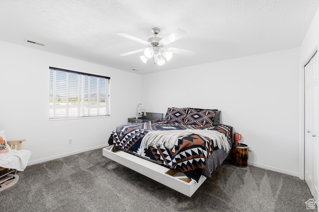 Bedroom featuring carpet floors, baseboards, a ceiling fan, a closet, and a textured ceiling