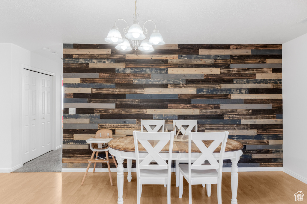Dining space featuring wooden walls, a chandelier, wood finished floors, and baseboards