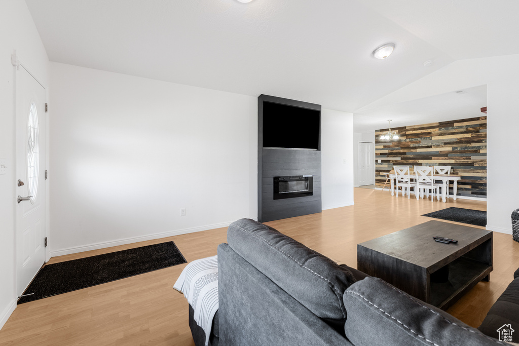Living room with wood finished floors, vaulted ceiling, a fireplace, and baseboards