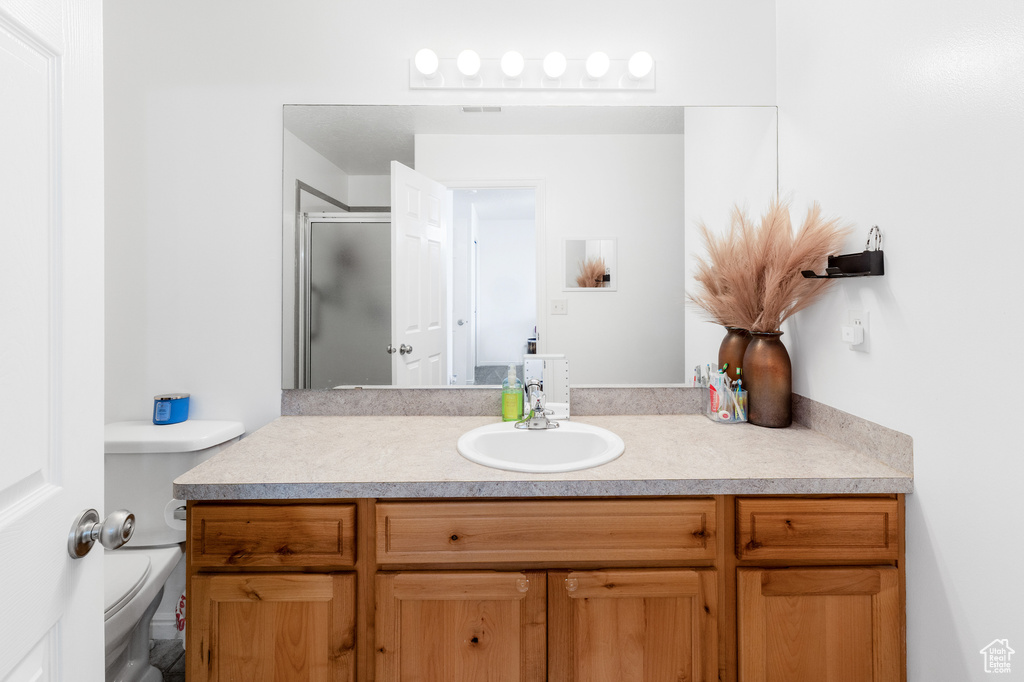 Full bath with vanity, toilet, and a stall shower