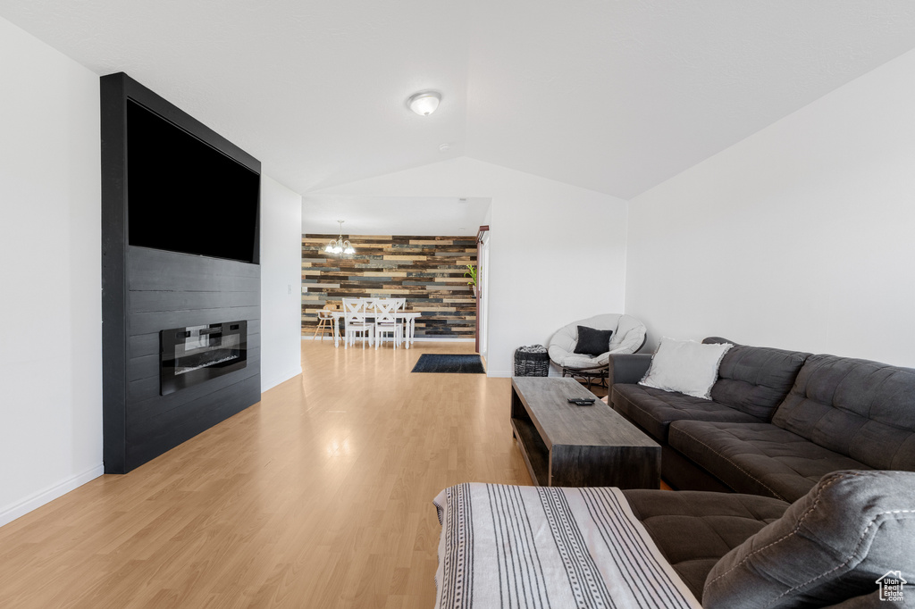 Living room featuring lofted ceiling, light wood-type flooring, baseboards, and a fireplace