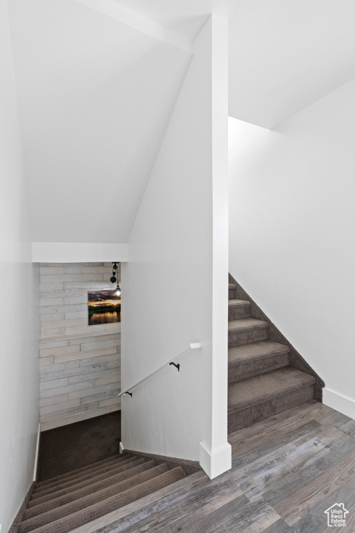 Stairway featuring vaulted ceiling and wood finished floors