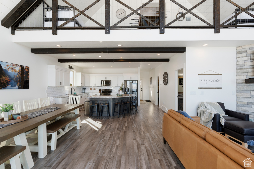 Living area featuring a high ceiling, dark wood-style floors, beam ceiling, and recessed lighting