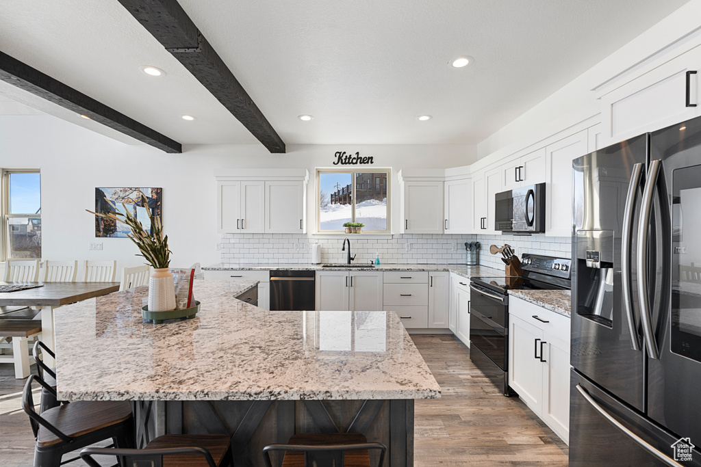 Kitchen with stainless steel fridge, black electric range, dishwasher, a sink, and a breakfast bar area