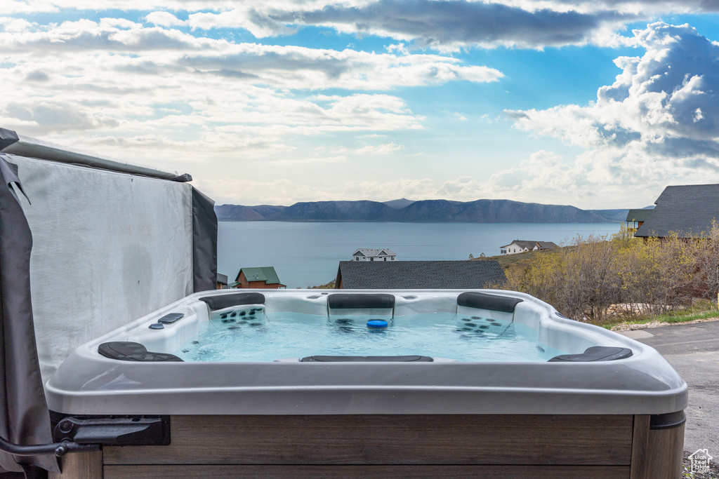 View of patio featuring a hot tub and a water and mountain view