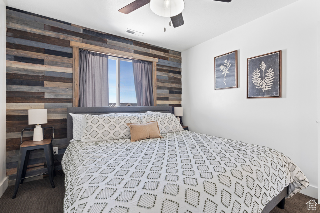 Bedroom featuring wood walls, carpet flooring, an accent wall, and a ceiling fan
