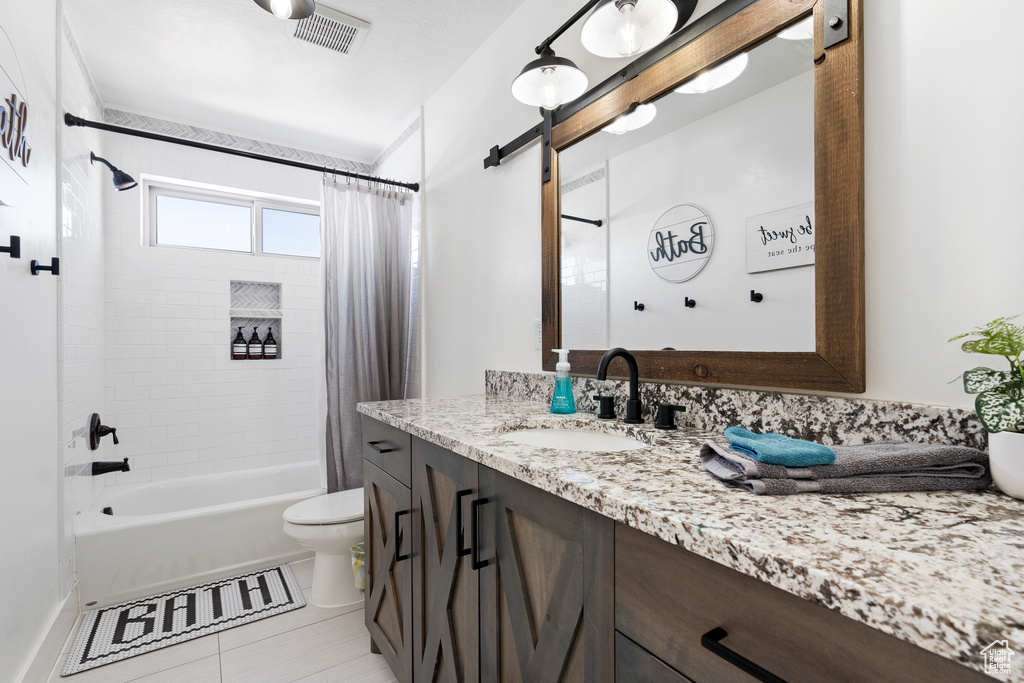 Bathroom featuring vanity, shower / tub combo with curtain, toilet, and tile patterned floors