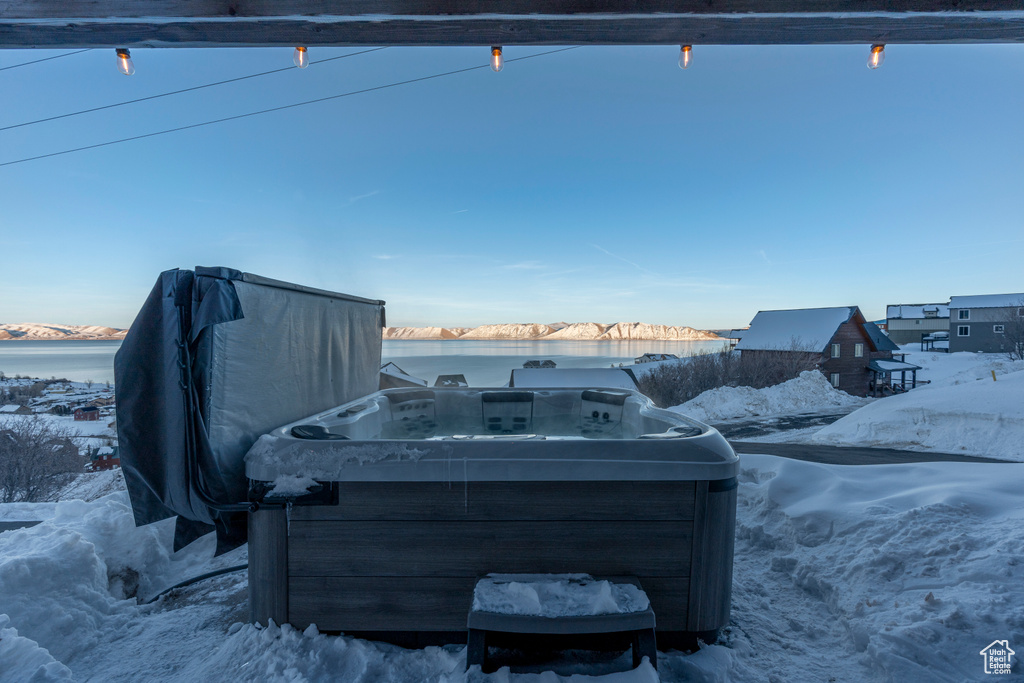 Snow covered patio with a hot tub and a water view