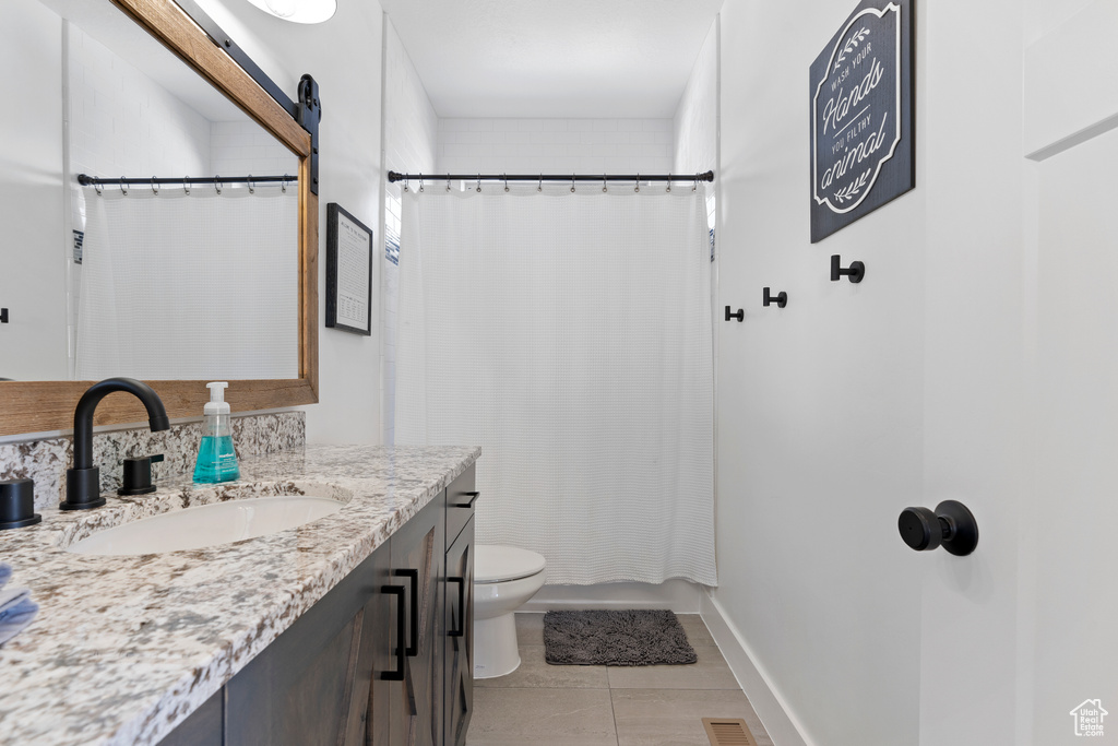 Full bath featuring vanity, toilet, tile patterned floors, shower / bathtub combination with curtain, and baseboards