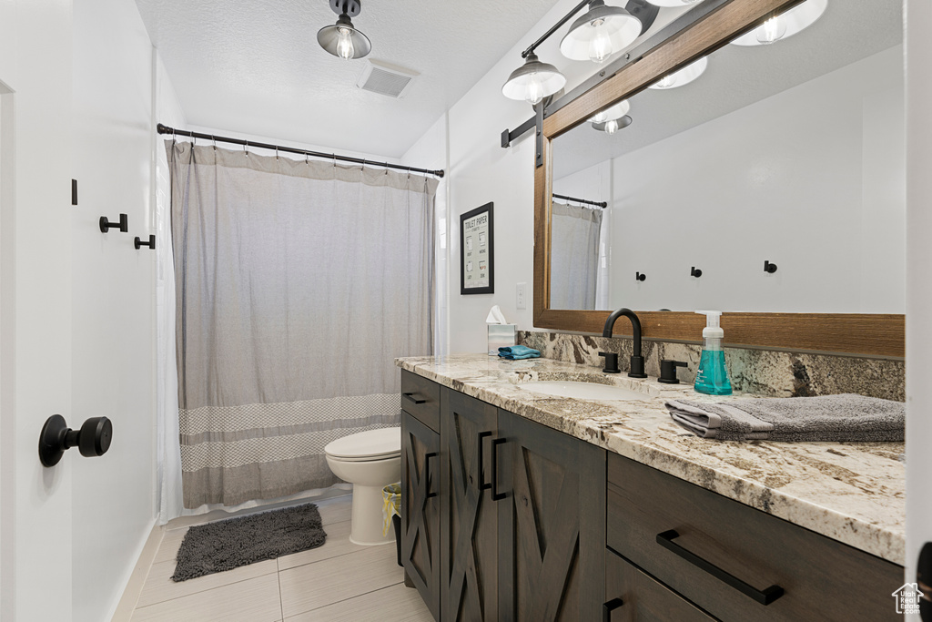 Full bath featuring toilet, vanity, and tile patterned flooring