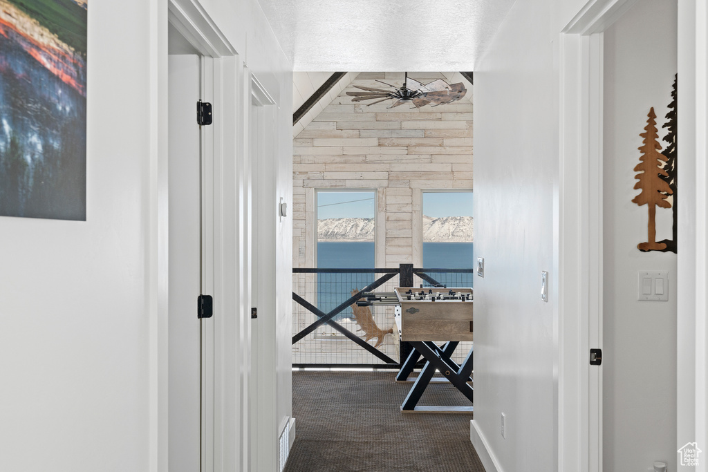 Hallway with dark colored carpet, a water view, and baseboards