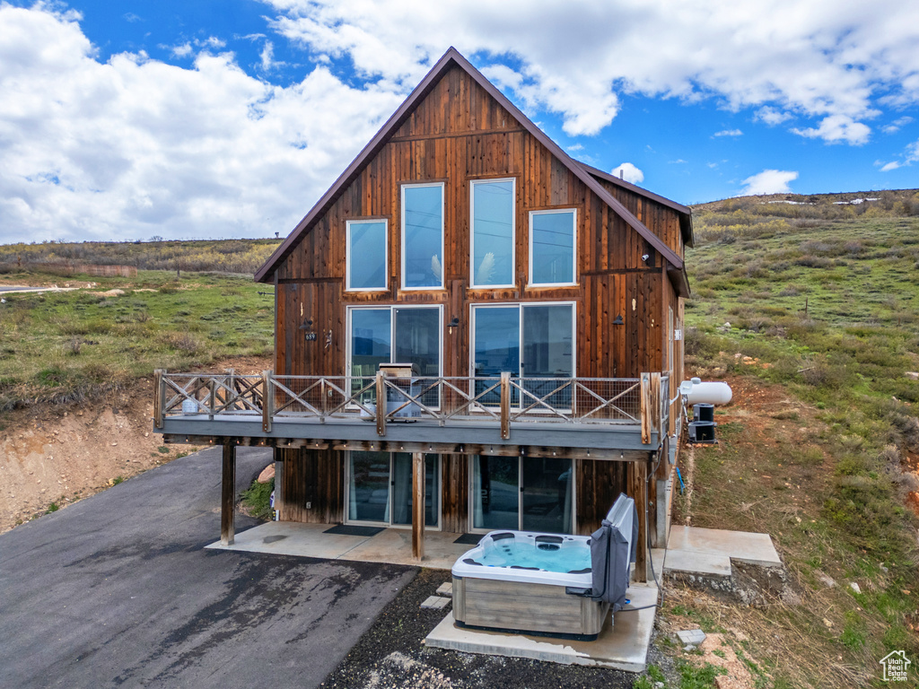 Rear view of house featuring a hot tub, a deck, and a patio area