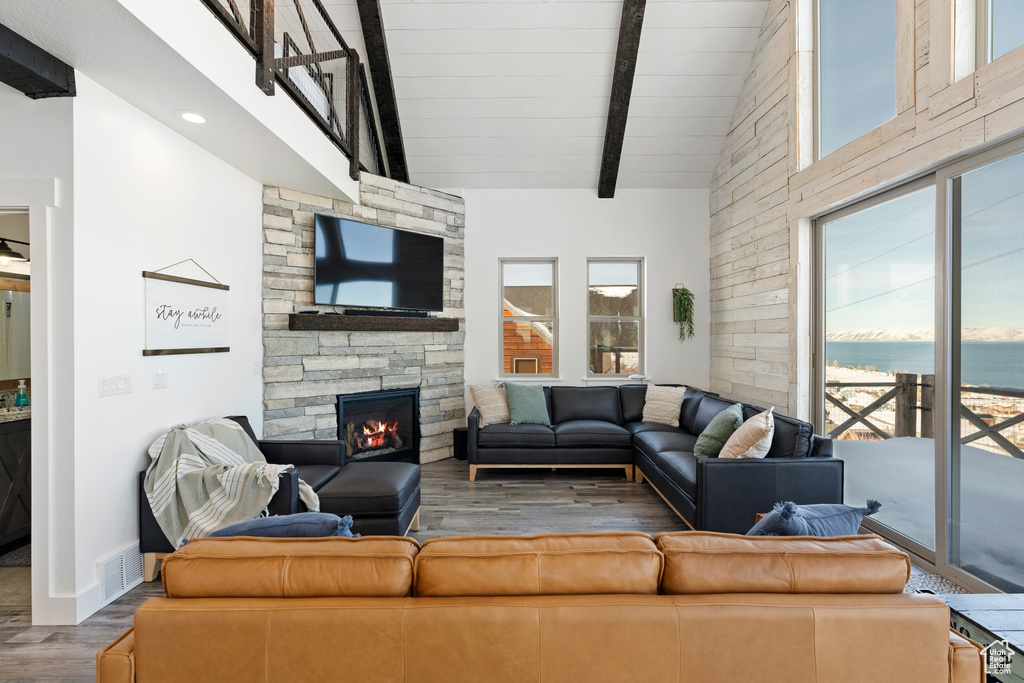 Living area featuring a stone fireplace, wood finished floors, baseboards, wood ceiling with exposed beams, and recessed lighting