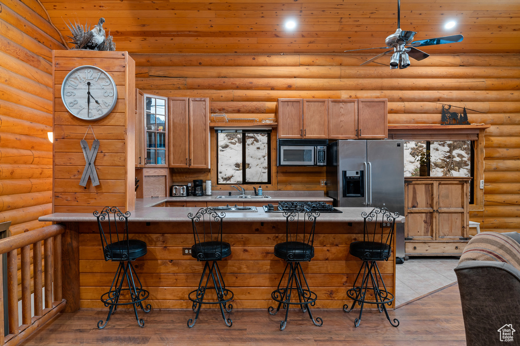 Kitchen with a breakfast bar, appliances with stainless steel finishes, ceiling fan, a peninsula, and wood ceiling
