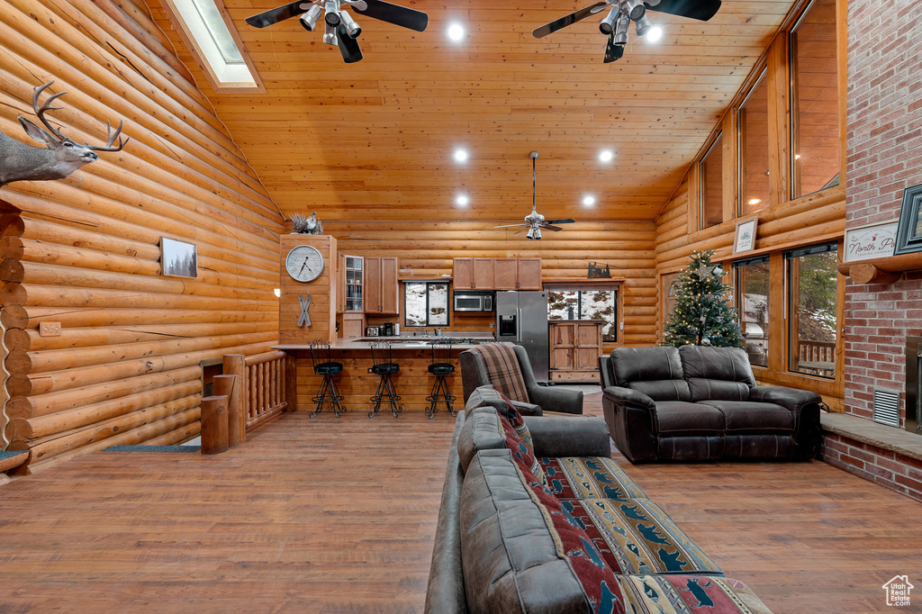 Living room featuring a ceiling fan, high vaulted ceiling, wood ceiling, log walls, and wood finished floors