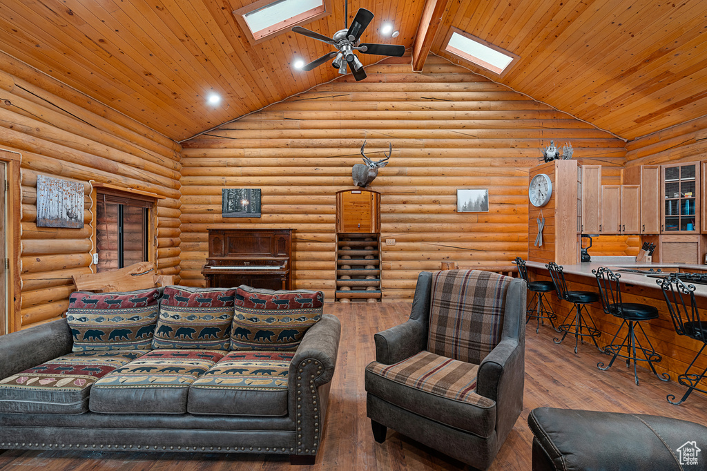 Living area with high vaulted ceiling, a skylight, wooden ceiling, wood-type flooring, and recessed lighting