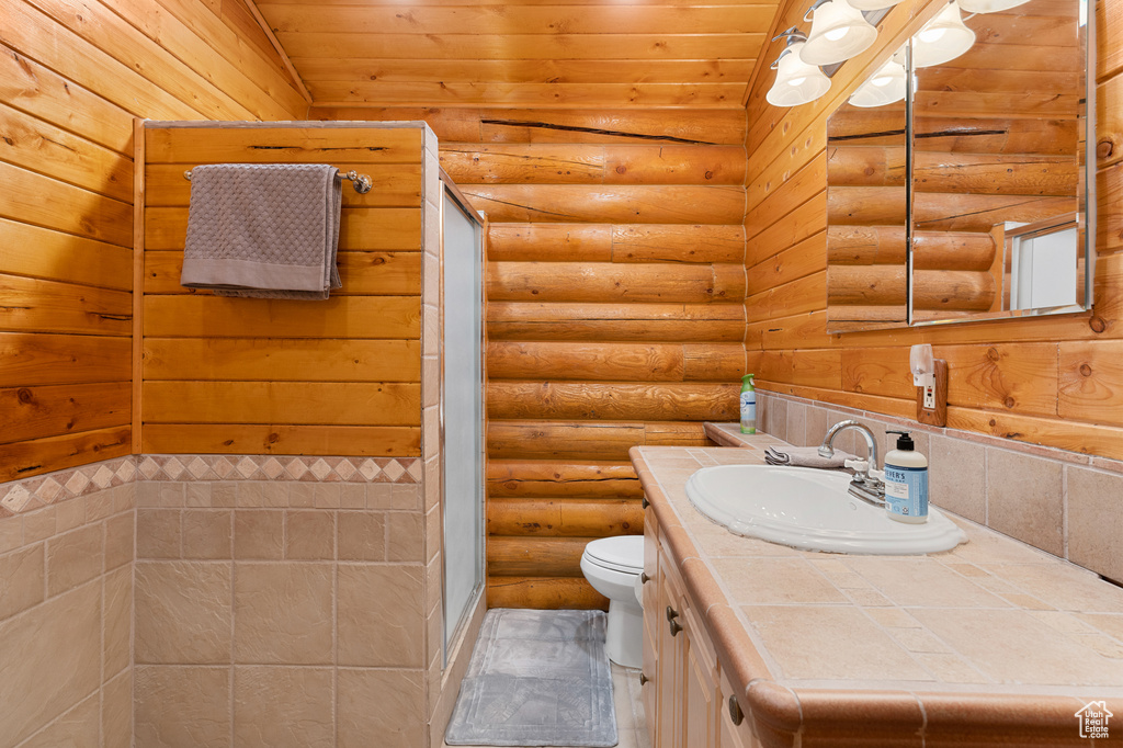Bathroom featuring toilet, vanity, log walls, wood ceiling, and a stall shower