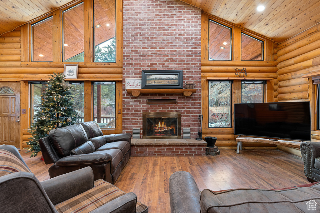 Living room featuring high vaulted ceiling, a fireplace, log walls, wood ceiling, and hardwood / wood-style flooring