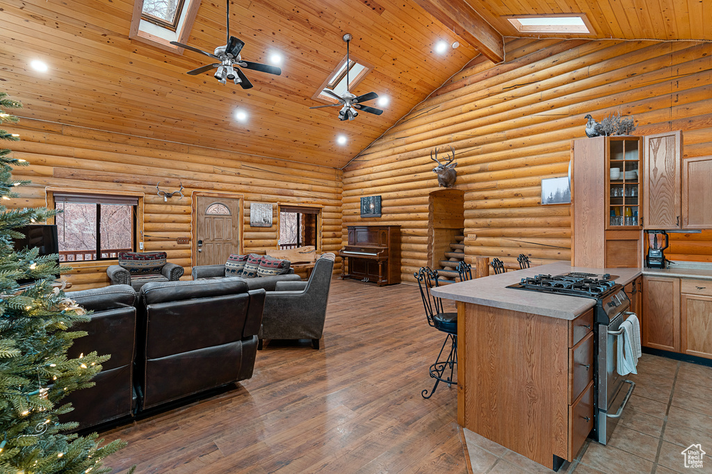 Interior space featuring a skylight, high vaulted ceiling, a ceiling fan, wooden ceiling, and recessed lighting