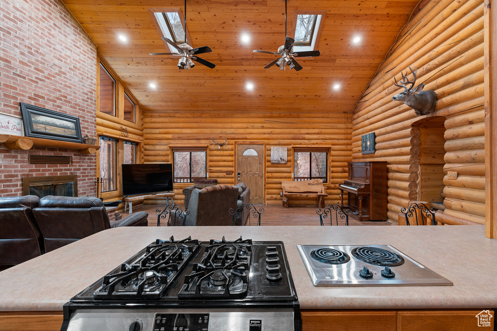 Kitchen featuring a skylight, high vaulted ceiling, wooden ceiling, a fireplace, and open floor plan