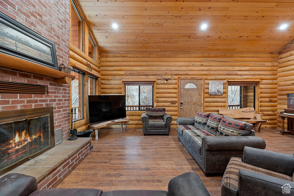 Living area with high vaulted ceiling, rustic walls, a fireplace, wood finished floors, and wood ceiling