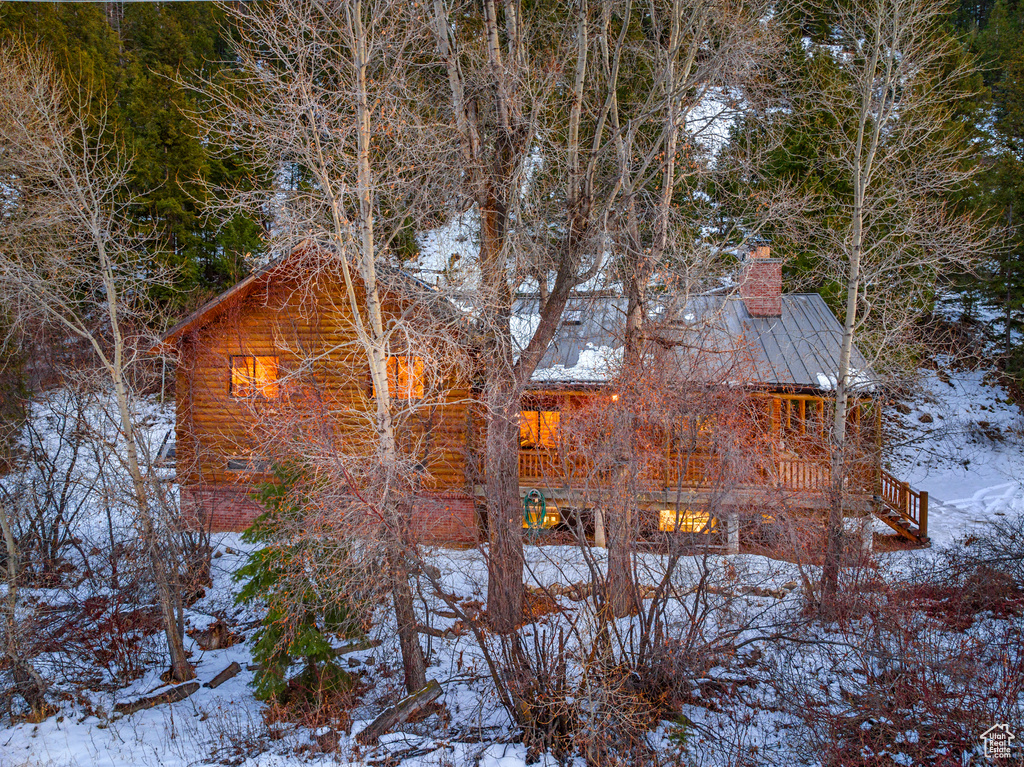 View of snow covered exterior featuring a chimney, a standing seam roof, and metal roof