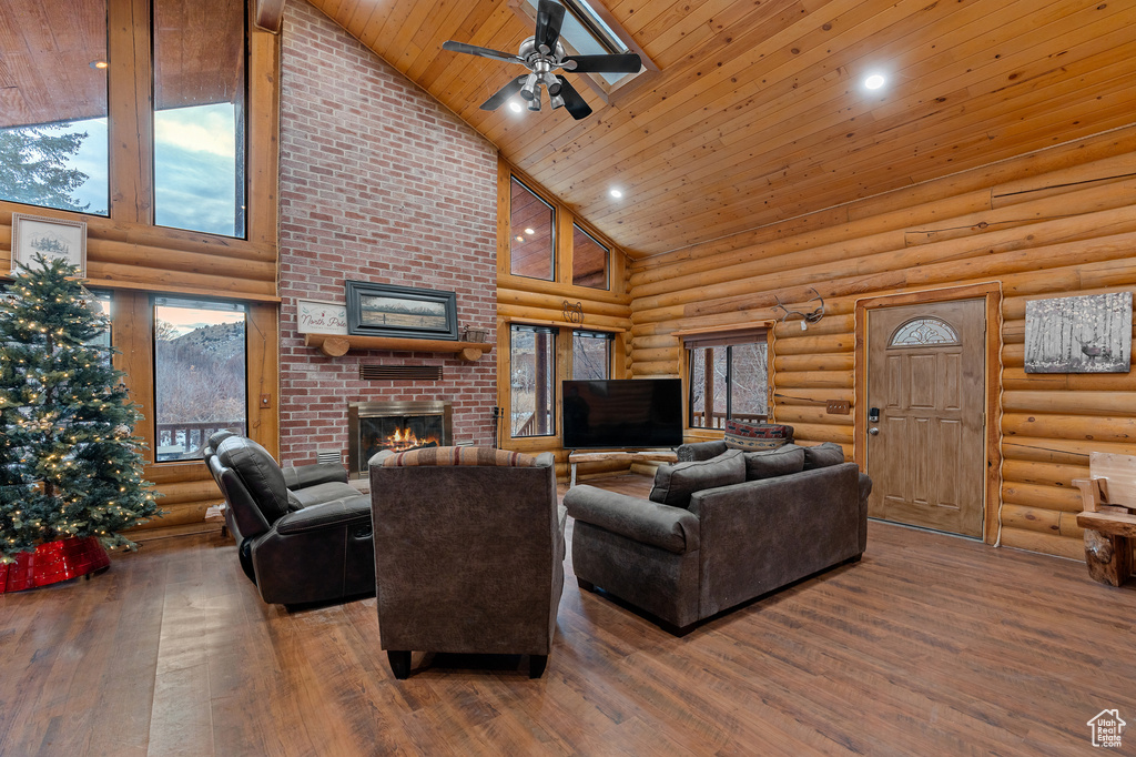 Living area featuring high vaulted ceiling, log walls, wood ceiling, a ceiling fan, and a fireplace