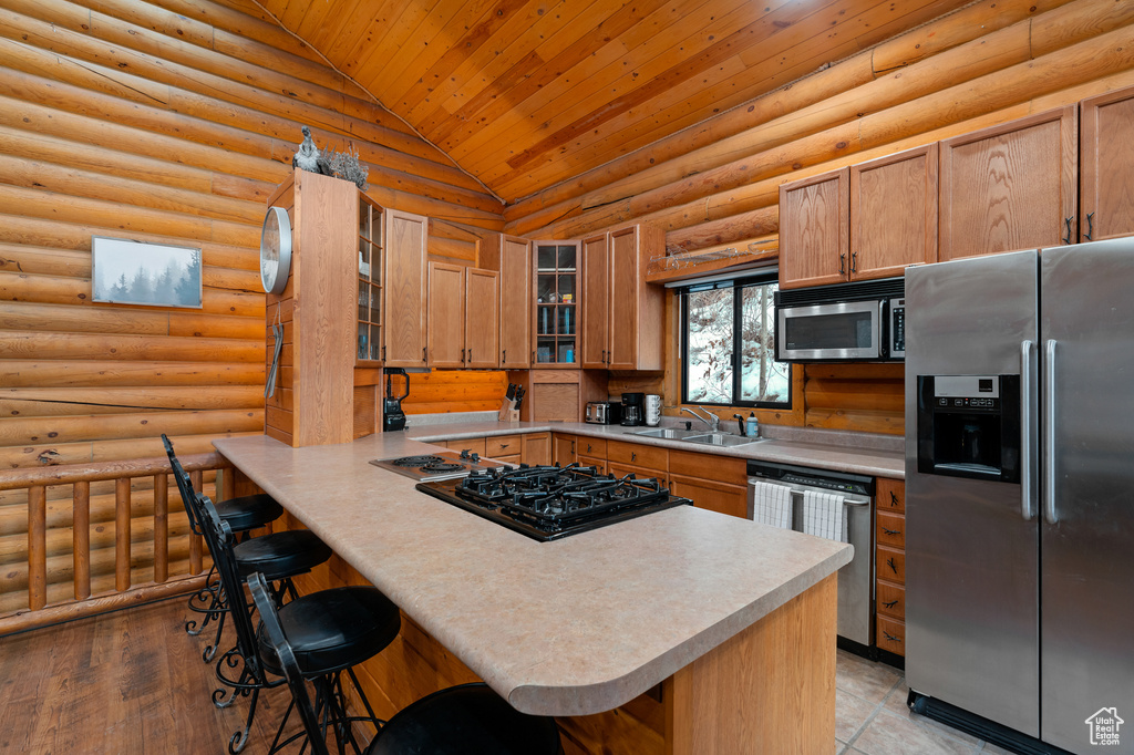 Kitchen featuring appliances with stainless steel finishes, lofted ceiling, a sink, wooden ceiling, and a breakfast bar