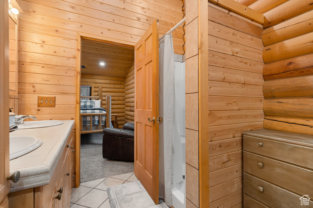 Bathroom with log walls, double vanity, tile patterned floors, and a shower with shower curtain