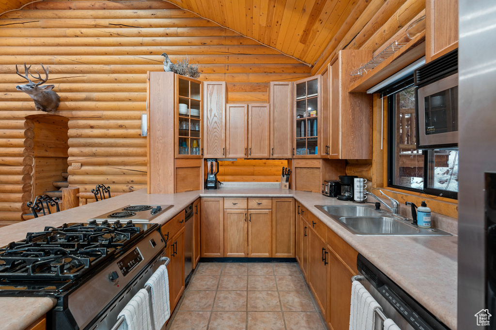 Kitchen with stainless steel appliances, a sink, wood ceiling, vaulted ceiling, and rustic walls