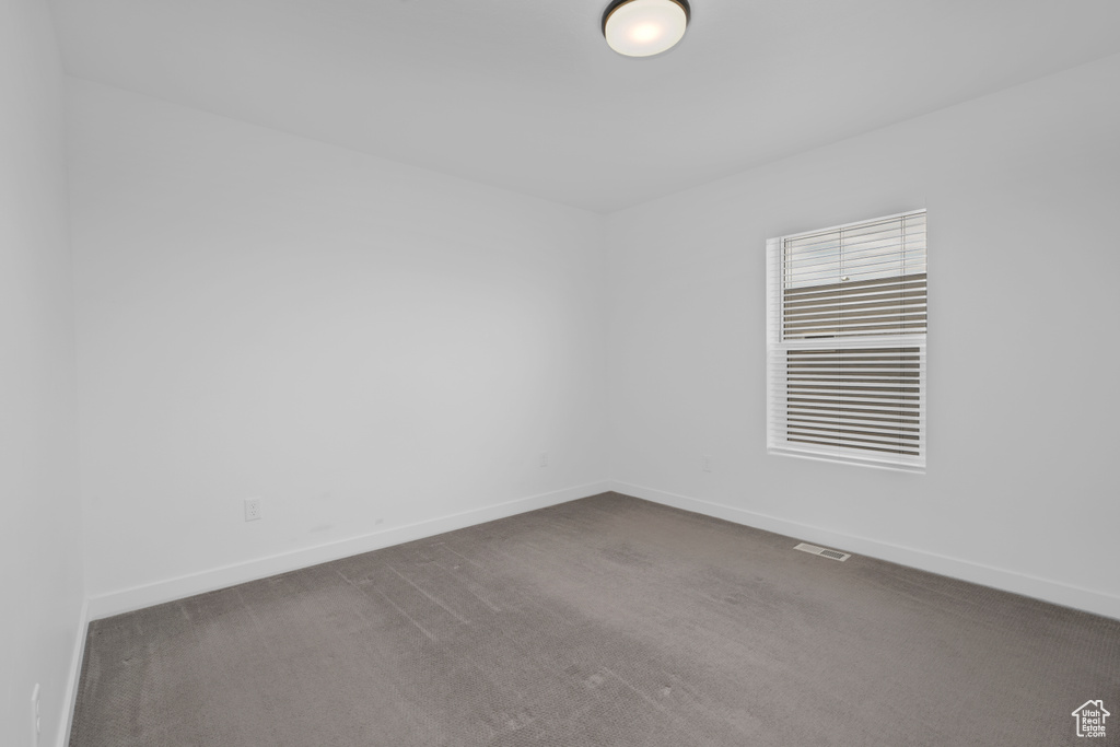 Unfurnished room featuring baseboards and dark colored carpet