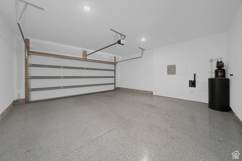 Garage featuring electric panel, a garage door opener, and recessed lighting