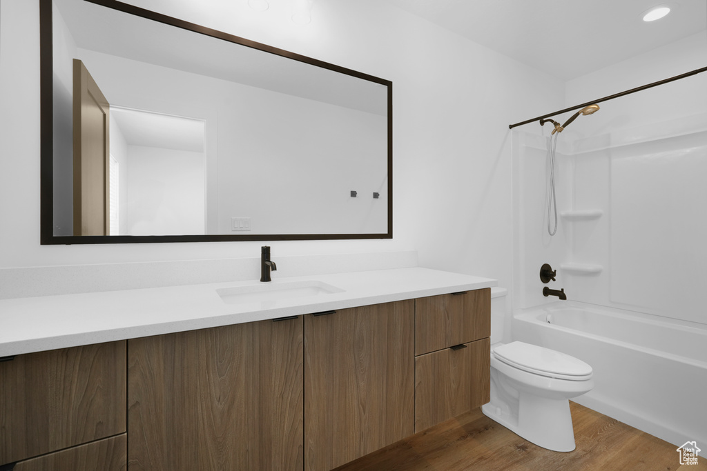 Full bathroom featuring toilet, vanity, wood finished floors, and shower / bath combination