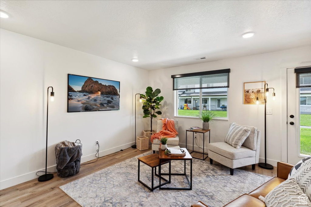 Living room featuring wood finished floors, plenty of natural light, baseboards, recessed lighting, and a textured ceiling