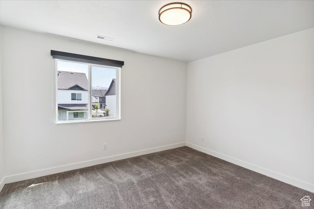 Unfurnished room featuring dark colored carpet and baseboards