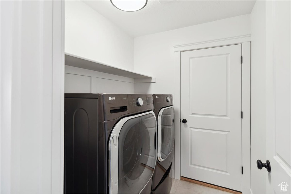 Washroom featuring washing machine and clothes dryer and light tile patterned floors