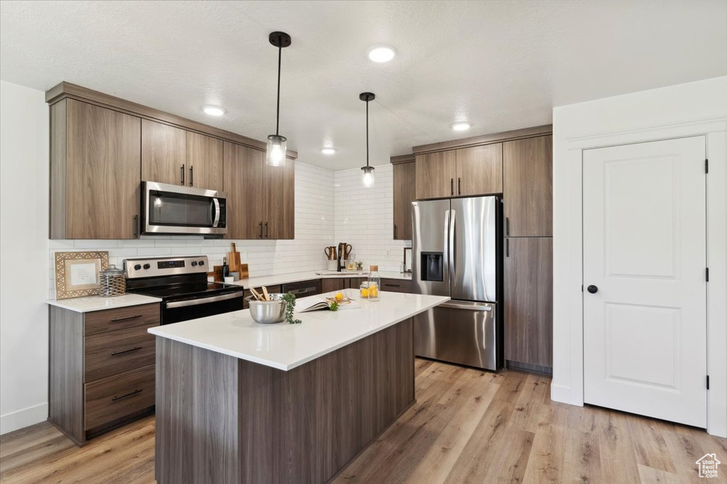 Kitchen with appliances with stainless steel finishes, backsplash, and light countertops