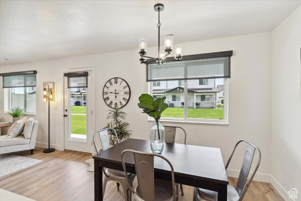 Dining space with plenty of natural light, a chandelier, light wood-style flooring, and baseboards